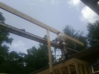 Carpenter setting a ridge beam over a new addition frame — Ice Dam Removal by Roofing Brothers in Neal