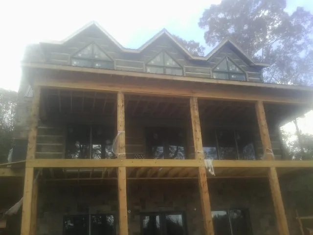 Dormers and porch framing on a large log home under construction — Roof Coating work by our crew in Neal