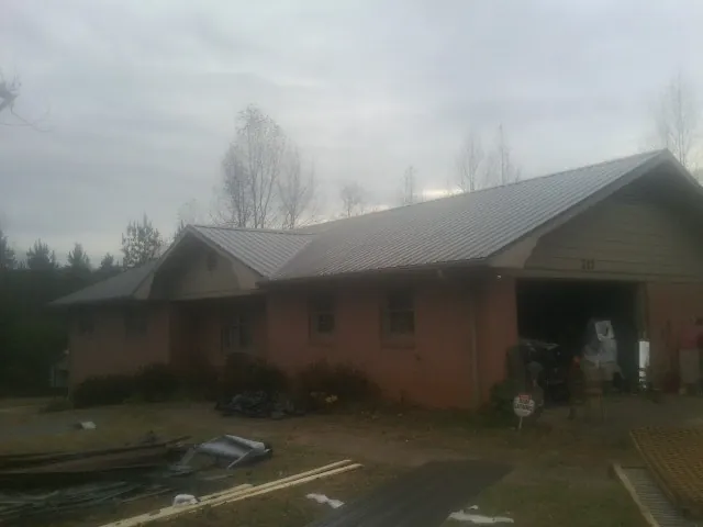 Gray metal roof on a stucco house with an attached garage in Neal