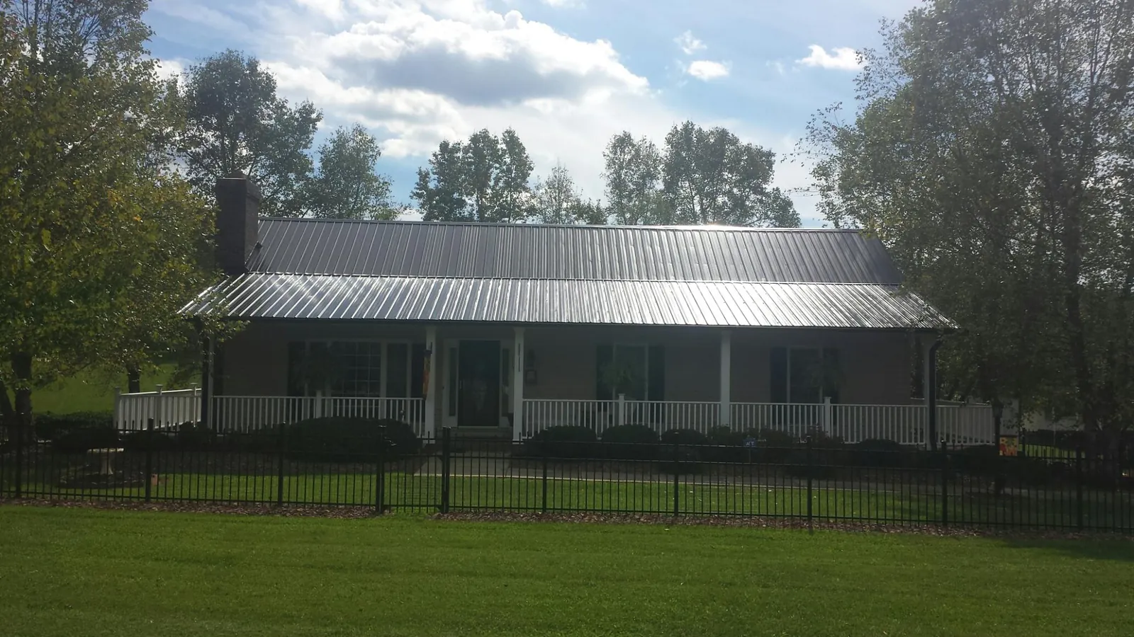 Gray metal roof on a brick ranch with a full width front porch — Gutter Guard Installation work by our crew in Neal
