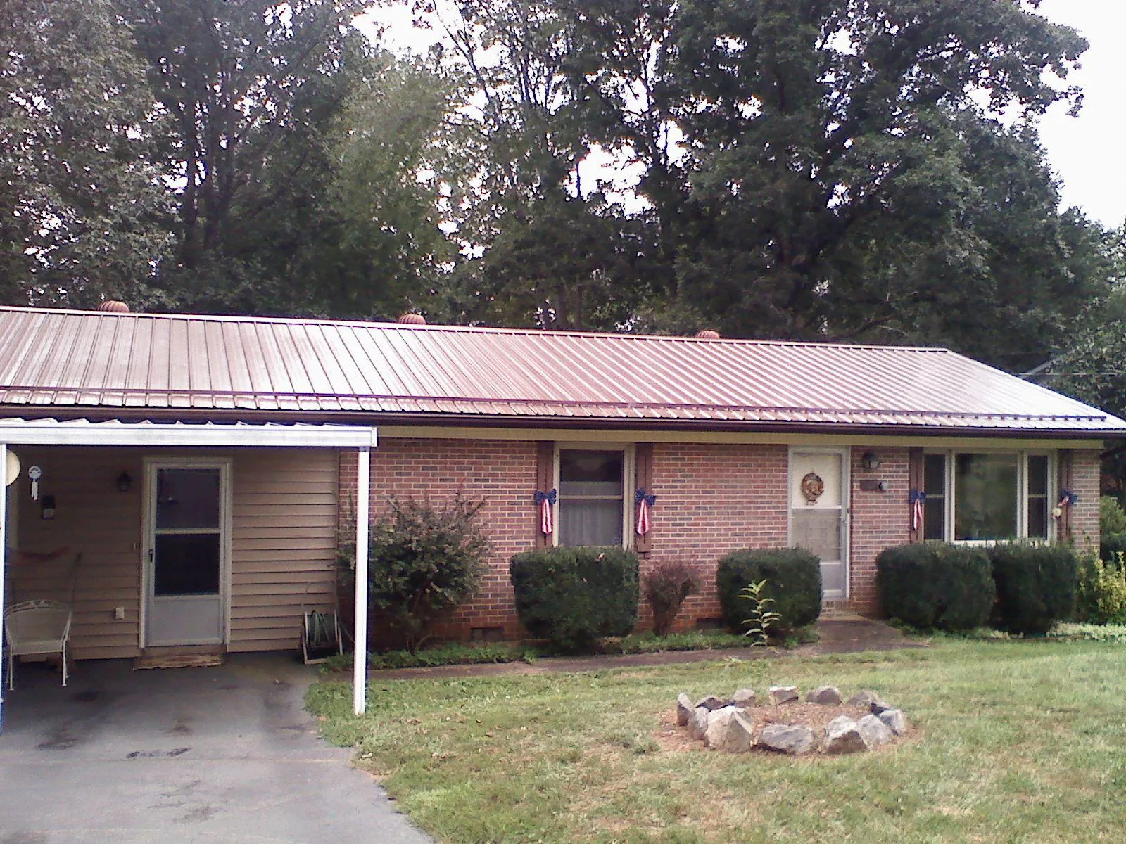 Bronze metal roof and carport on a brick ranch home — Roof Repair work by our crew in Neal