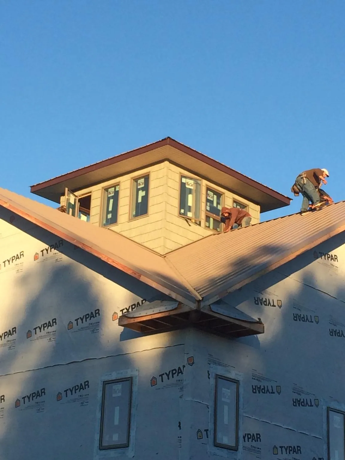 Roofers working around a rooftop cupola on a new metal roof at sunset — Roof Waterproofing in Neal by Roofing Brothers